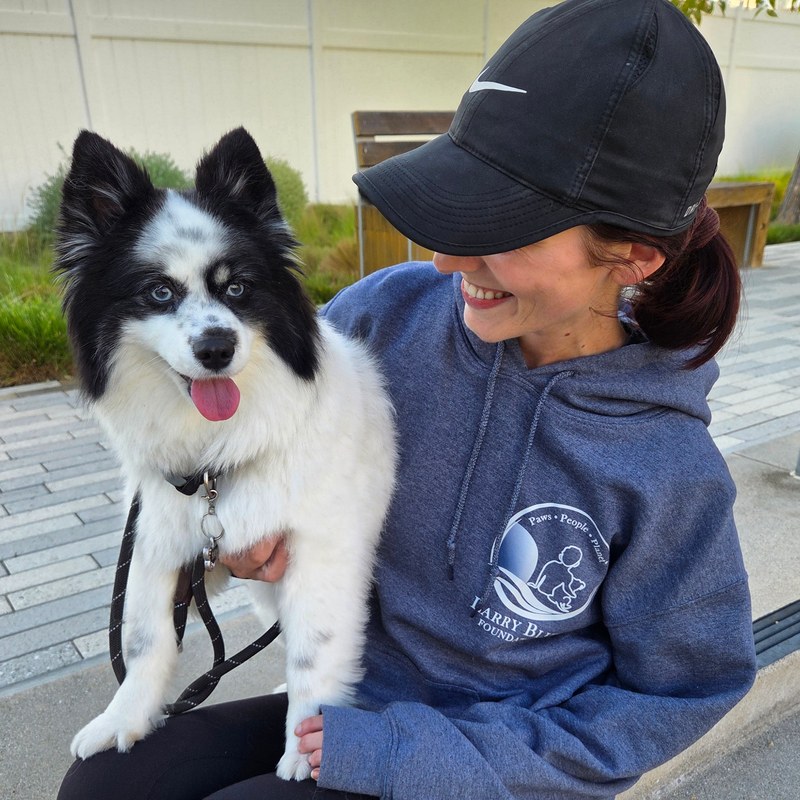 A supporter wearing the Larry Blue Foundation hoodie, front crest visible, holding her dog
