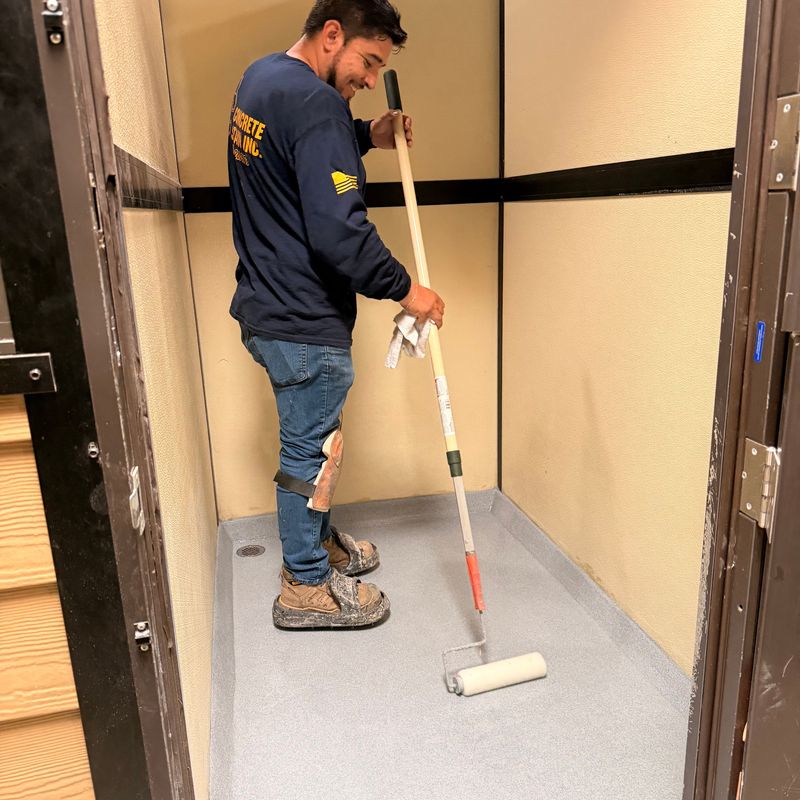 A worker rolls a fresh sealed coat onto a rebuilt kennel floor