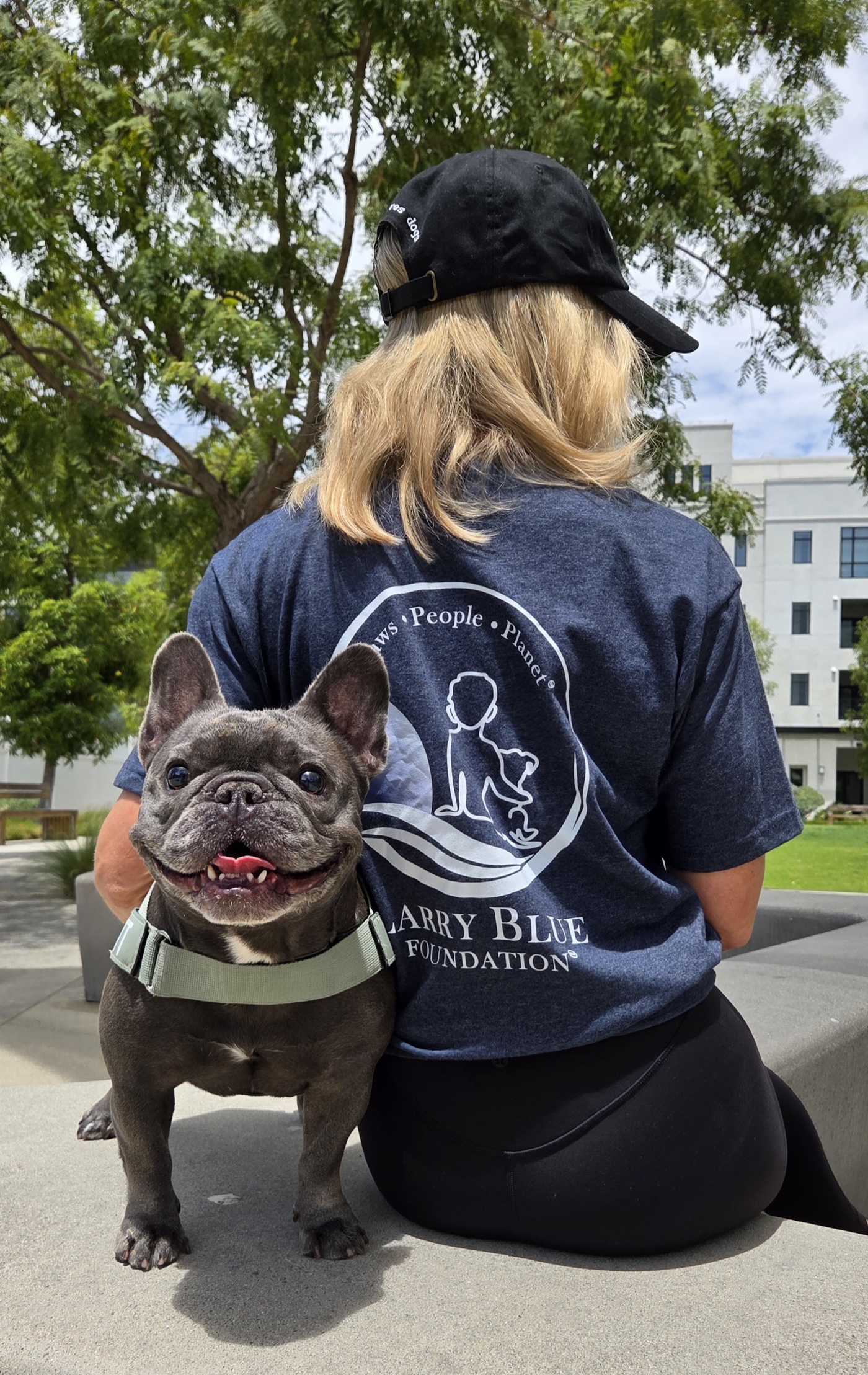 A French bulldog beside a volunteer wearing a Larry Blue Foundation shirt